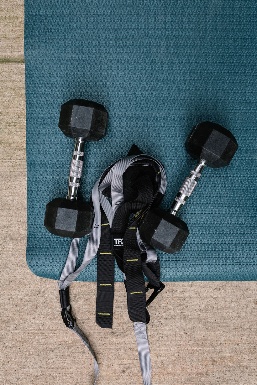 a pair of dumbbells and TRX strap on a blue mat
