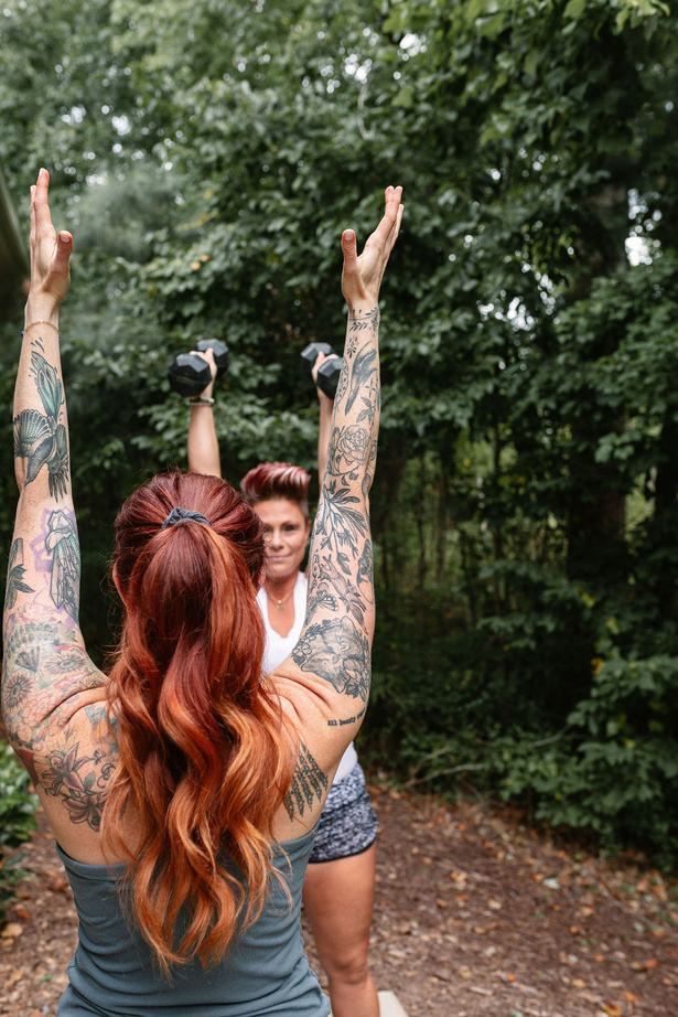 two people with tattoos lifting weights in the woods
